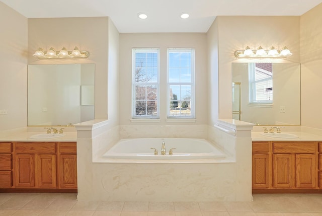 bathroom featuring tile patterned flooring, two vanities, a sink, and a bath