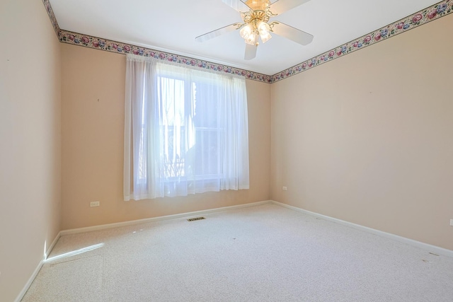 carpeted spare room featuring a ceiling fan, visible vents, and baseboards