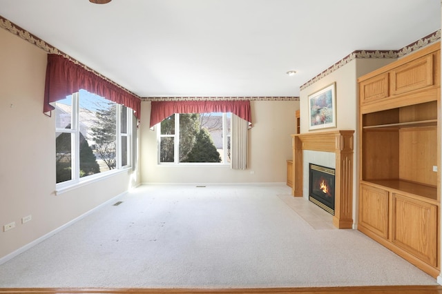 unfurnished living room featuring baseboards, light colored carpet, and a tiled fireplace