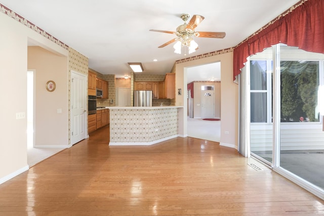 unfurnished living room with ceiling fan, light wood finished floors, and baseboards