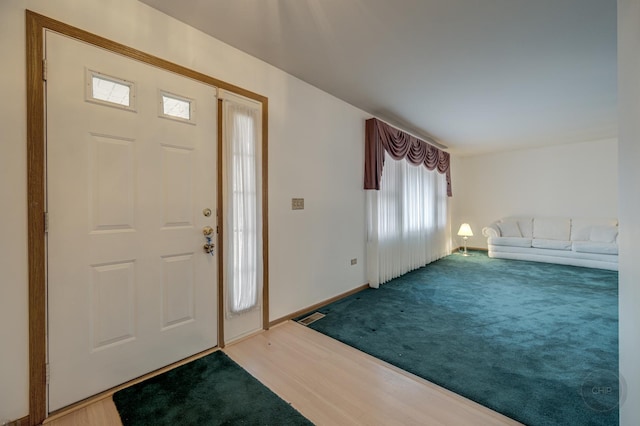 carpeted foyer featuring wood finished floors, visible vents, and baseboards