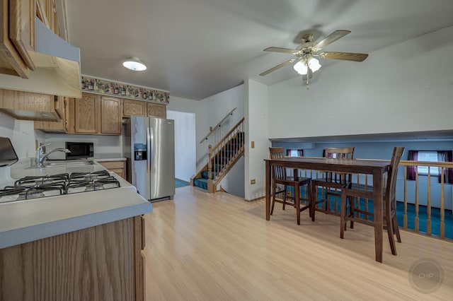 kitchen with stainless steel refrigerator with ice dispenser, light countertops, light wood-style flooring, ceiling fan, and black microwave