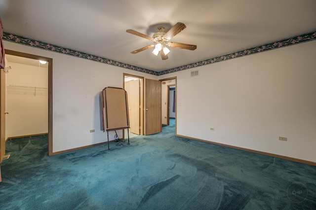 unfurnished bedroom with carpet floors, a walk in closet, visible vents, and baseboards