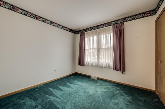 spare room featuring carpet floors and baseboards