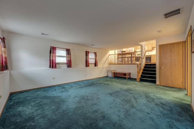 unfurnished living room featuring carpet, visible vents, stairway, and baseboards