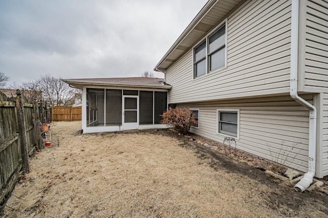 back of property with a fenced backyard and a sunroom