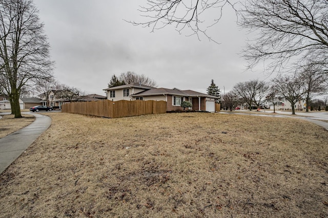 view of front of house featuring a garage, brick siding, and fence