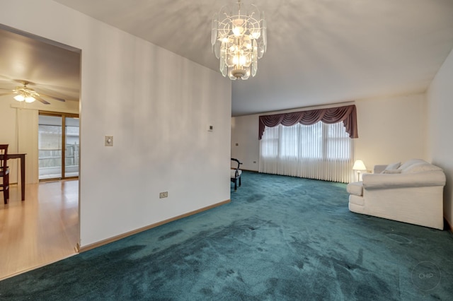 unfurnished living room featuring carpet, baseboards, and ceiling fan with notable chandelier