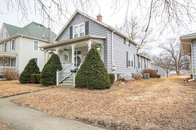 view of front of property featuring covered porch, central AC, and a chimney