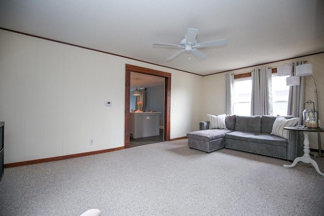 living room with ornamental molding, carpet, ceiling fan, and baseboards