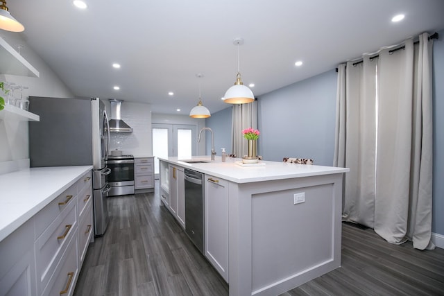 kitchen with recessed lighting, a sink, wall chimney range hood, appliances with stainless steel finishes, and dark wood finished floors