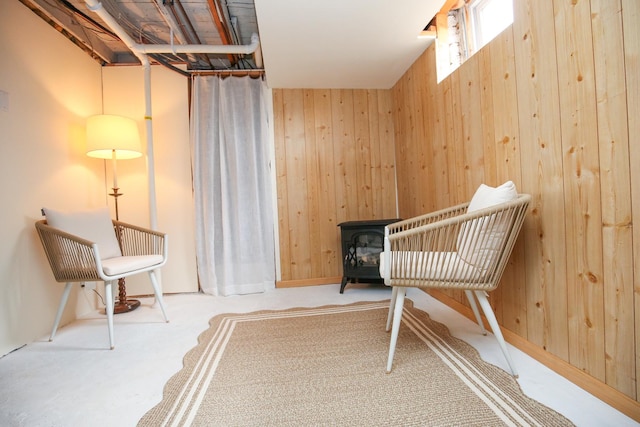 unfurnished room featuring a wood stove, wood walls, and carpet floors