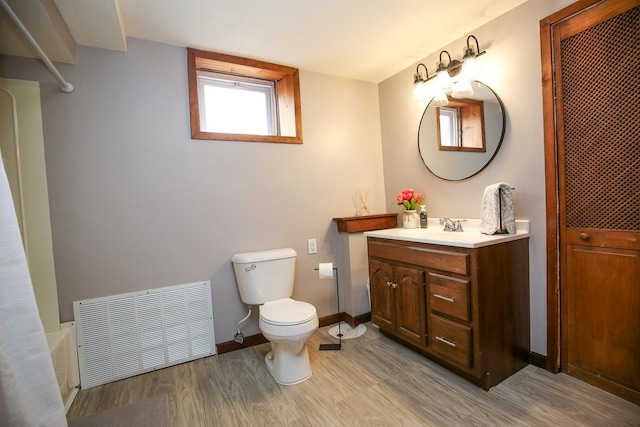 bathroom with toilet, wood finished floors, vanity, visible vents, and baseboards