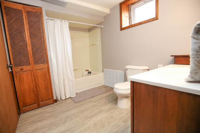 bathroom featuring toilet, wood finished floors, vanity, visible vents, and shower / bath combination with curtain