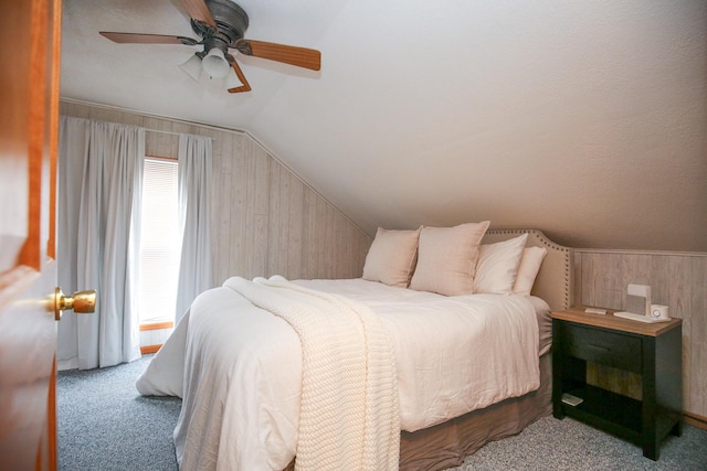 carpeted bedroom featuring lofted ceiling, a ceiling fan, and wooden walls