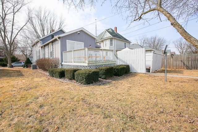 rear view of property featuring a deck, central AC unit, a lawn, and fence