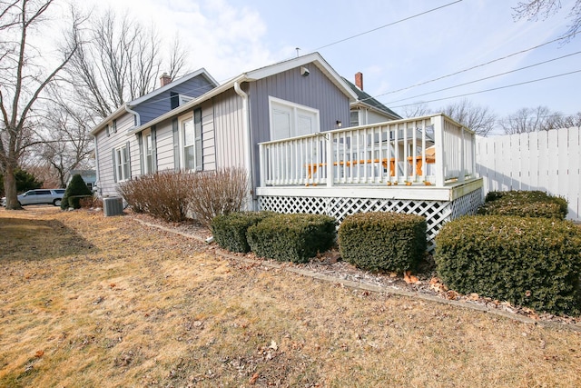 view of side of property featuring central AC unit, a chimney, a wooden deck, and fence