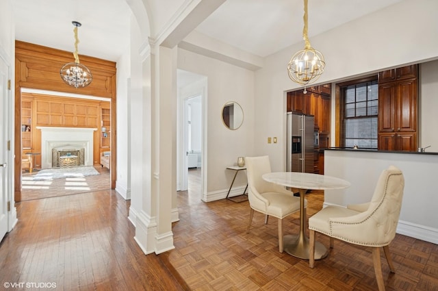 dining room featuring a chandelier, ornate columns, a fireplace, and baseboards