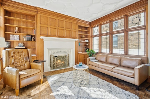 living area with built in shelves, a healthy amount of sunlight, and a lit fireplace