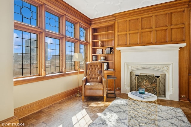 sitting room with built in shelves, a fireplace, a wealth of natural light, and baseboards