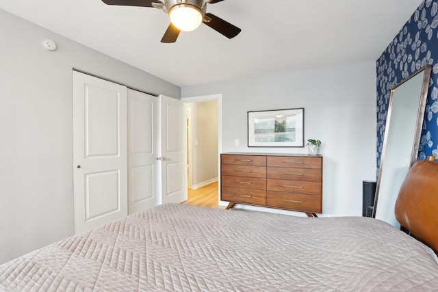 bedroom with light wood-type flooring, a closet, ceiling fan, and baseboards