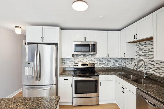 kitchen featuring backsplash, white cabinetry, stainless steel appliances, and a sink