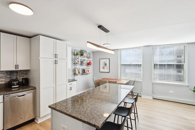 kitchen featuring light wood-style floors, a breakfast bar, backsplash, and stainless steel dishwasher