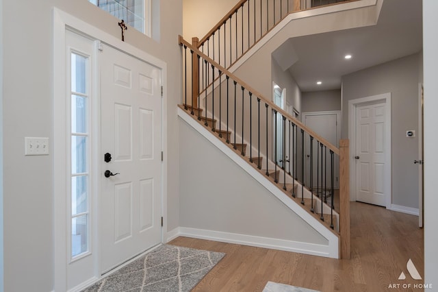 foyer entrance featuring recessed lighting, a high ceiling, wood finished floors, baseboards, and stairway