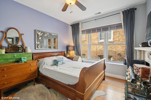 bedroom featuring ceiling fan, wood finished floors, visible vents, and baseboards