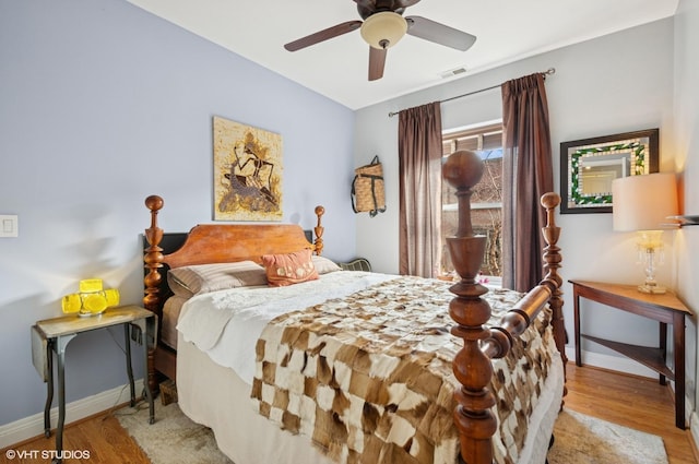 bedroom featuring light wood-style floors, baseboards, visible vents, and ceiling fan