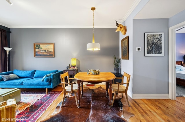 dining space featuring ornamental molding, baseboards, and wood finished floors