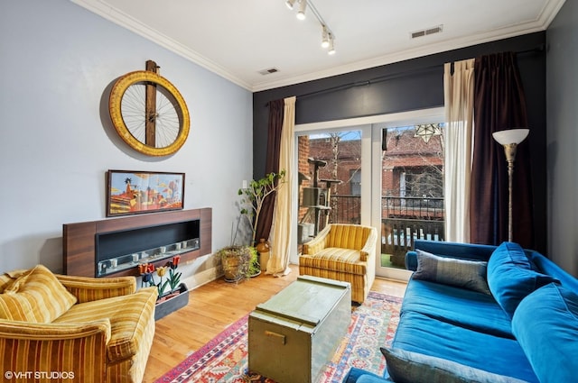 living area with visible vents, track lighting, ornamental molding, and wood finished floors