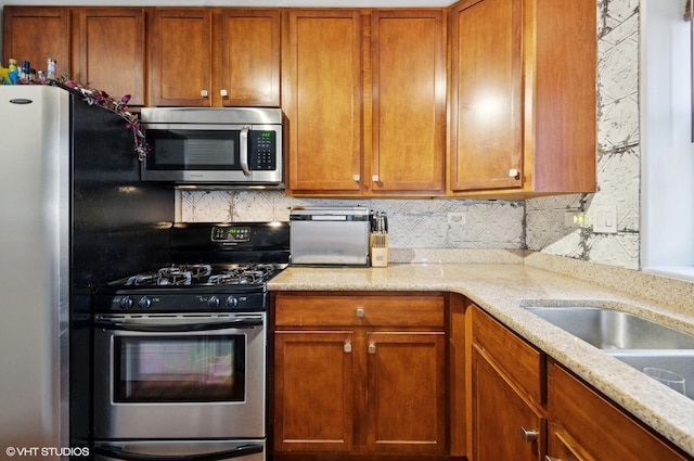 kitchen with brown cabinets, light stone counters, stainless steel appliances, and backsplash