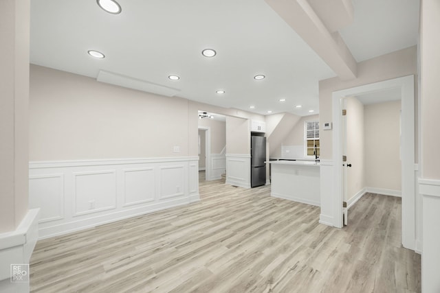 spare room featuring light wood finished floors, a decorative wall, wainscoting, and recessed lighting