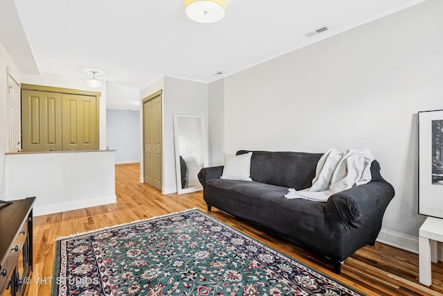 living room featuring baseboards, visible vents, and light wood finished floors