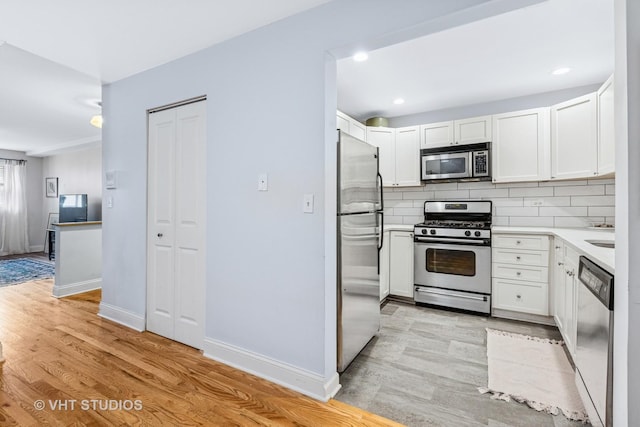 kitchen featuring light wood-style floors, stainless steel appliances, backsplash, and light countertops