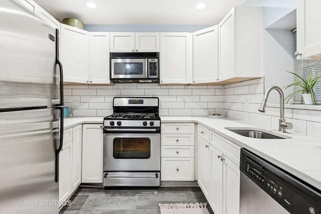 kitchen with appliances with stainless steel finishes, white cabinetry, a sink, and tasteful backsplash