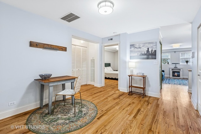 hall featuring light wood finished floors, visible vents, and baseboards