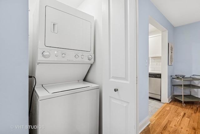 laundry area with stacked washer and dryer, light wood finished floors, and laundry area