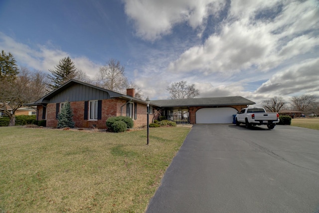 ranch-style house featuring brick siding, an attached garage, a chimney, and a front yard