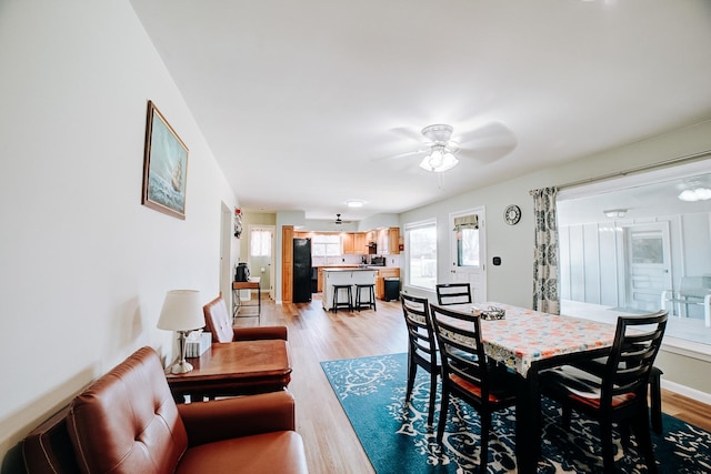 dining space featuring light wood finished floors, baseboards, and a ceiling fan