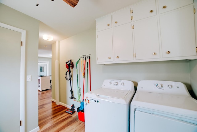 clothes washing area with washer and dryer, cabinet space, light wood-style floors, and baseboards