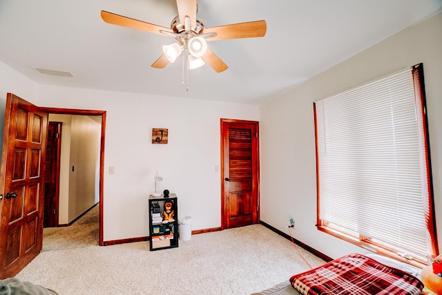 bedroom with visible vents, light colored carpet, baseboards, and ceiling fan