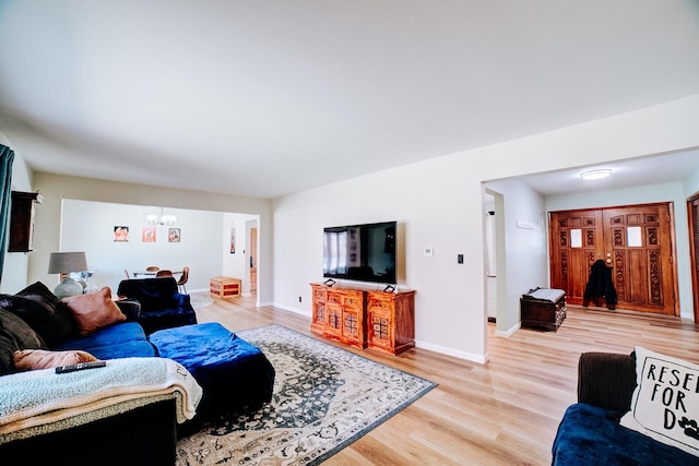 living area with an inviting chandelier, light wood-style floors, and baseboards