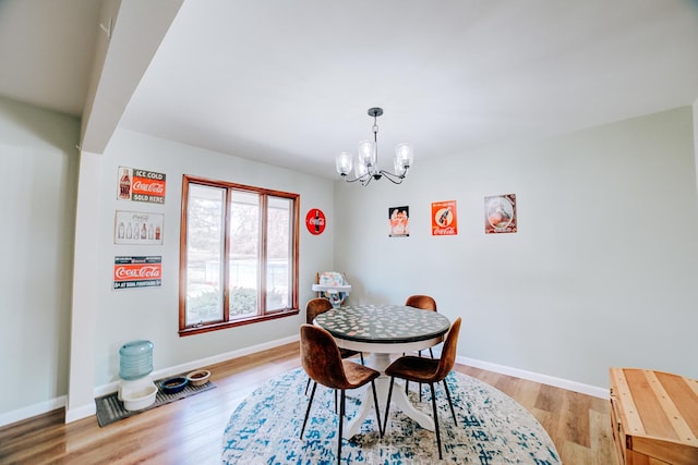 dining area with baseboards, light wood-type flooring, and an inviting chandelier