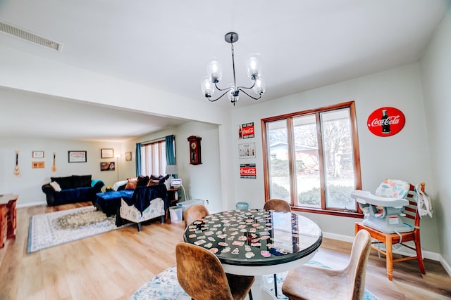 dining room with a notable chandelier, visible vents, light wood-style flooring, and baseboards