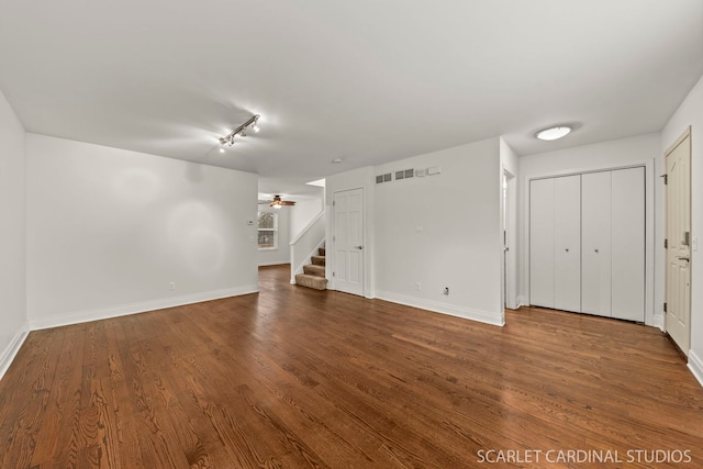 unfurnished living room featuring stairs, dark wood-style flooring, a ceiling fan, and baseboards