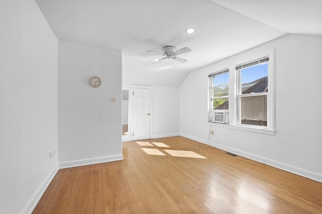 additional living space featuring visible vents, light wood-style floors, vaulted ceiling, ceiling fan, and baseboards