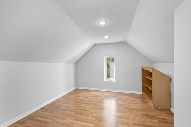 bonus room with light wood-style floors, lofted ceiling, and baseboards