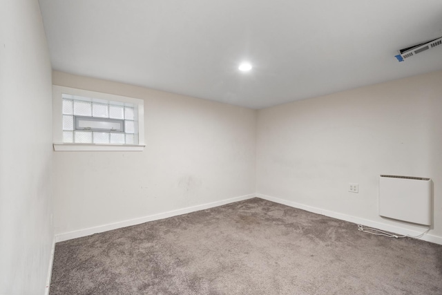 carpeted empty room featuring heating unit, baseboards, and visible vents